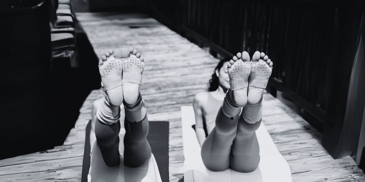 Two girls wearing socks doing yoga pose.