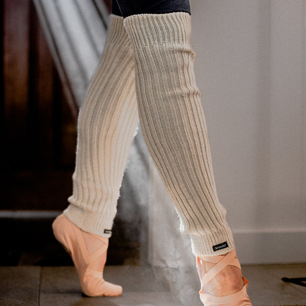 Legs of a woman in a ballet pose wearing the Knitido plus brand Wool Blend Ribbed Leg Warmer in the color TAN