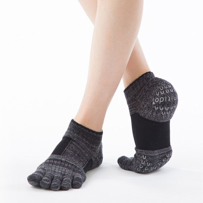 Woman's knee in black wearing Knitido plus brand Arch Support Heather Footie Grip Toe Socks With Power Pads product