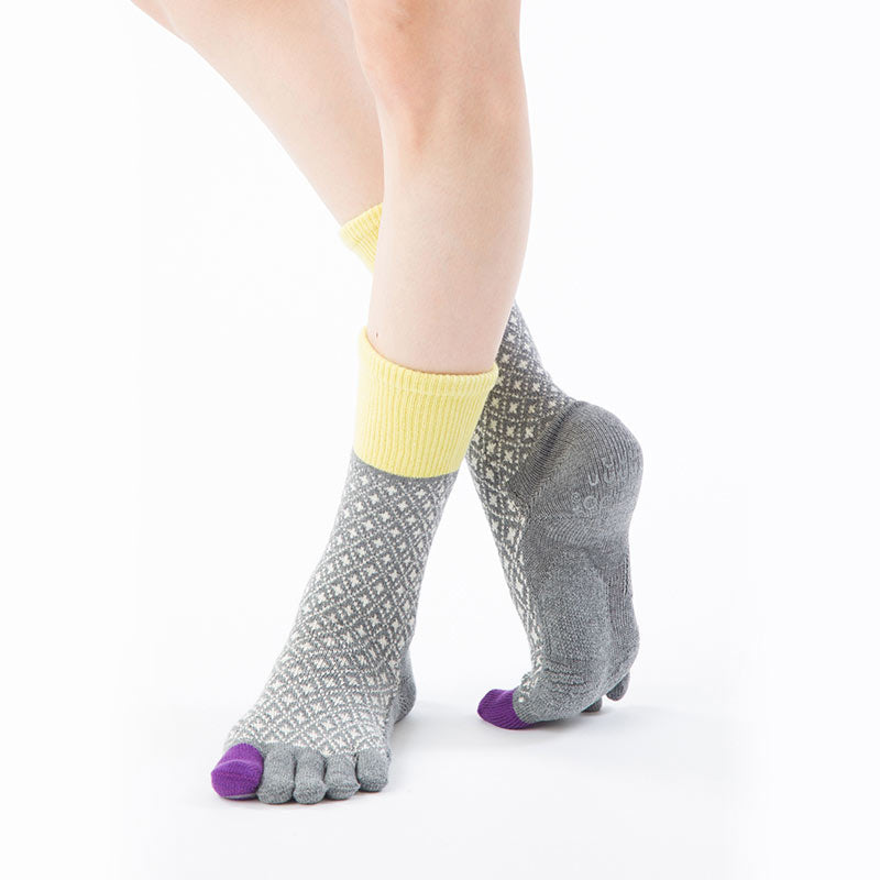 Front view of a woman wearing Knitido plus brand Diamond Midcalf Grip Toe Socks With Power Pads in Grey (with yellow and purple inserts)
