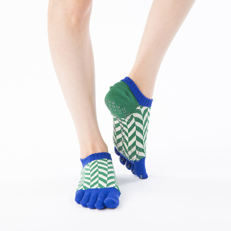 Front view of a woman's leg wearing Knitido plus brand Organic Cotton Herringbone Grip Socks in Green with blue inserts at the cuff and toe