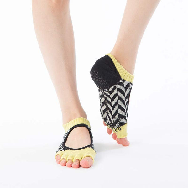 Front view of a woman's leg wearing a pair of Knitido plus brand Organic Cotton Herringbone Open Toe Liner Socks in black with yellow insert